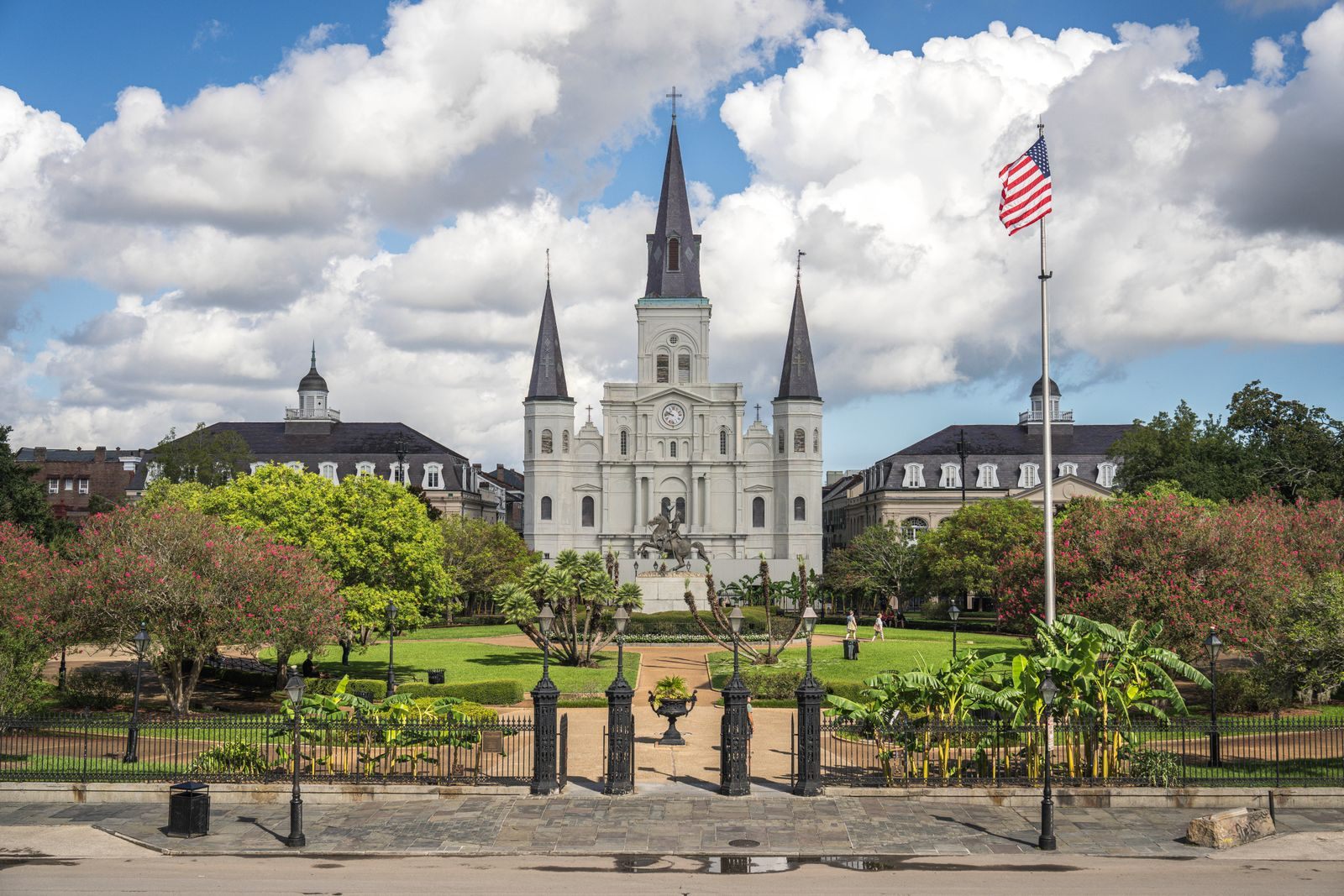 St. Louis Cathedral with its three white spires behind the gardens and fence of Jackson Square in New Orleans